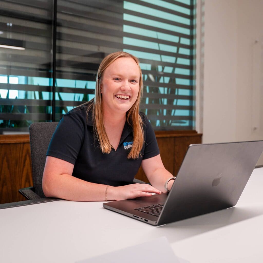 Friendly Midwest Roofing team member working on laptop in office.